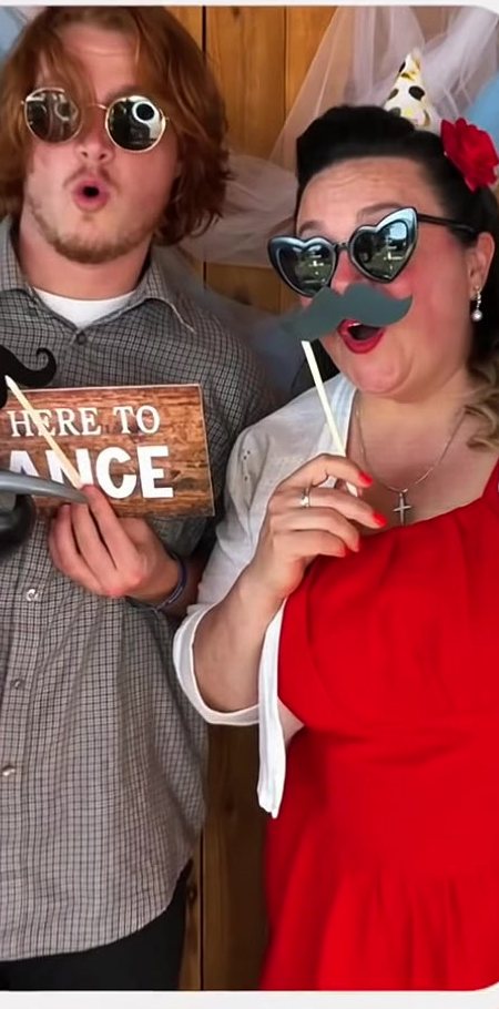 Newlyweds posing with props at the photo booth